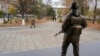 Un militar trece pe lângă statuia unui soldat, lângă sediul Grupului Operațional al Forțelor Ruse din Tiraspol.
