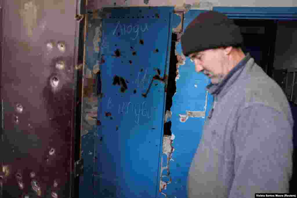 На дверях підвалу одного з житлових будинків у Часовому Яру видно пошкодження від осколків і напис, що повідомляє про перебування там мирних жителів. 56-річний Володимир слухає, як волонтери намагаються вмовити таких людей, як він, залишити місто