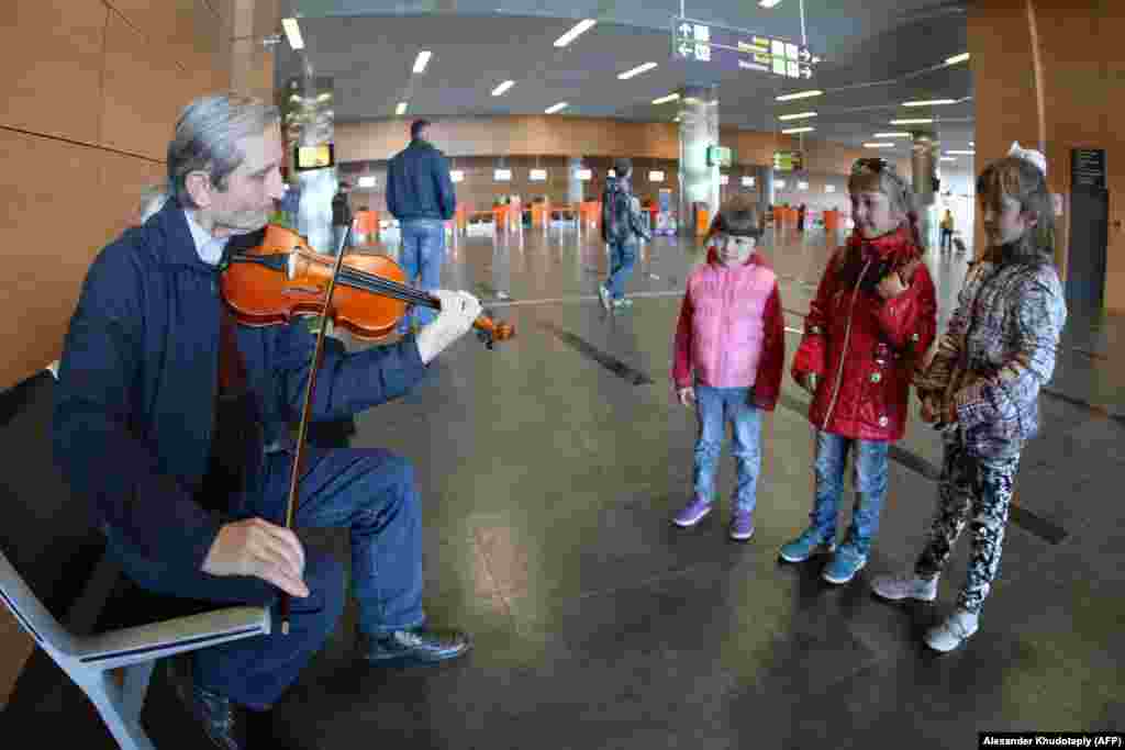 Children listen to a musician warming up before he performs inside the airport in March 2014. At the airport’s opening in May 2012, Ukraine’s deputy prime minister predicted that the sleek new facility's opening would "serve around 4 million passengers a year" by 2015.