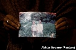 Захра Рамзан држи фотографија од нејзиниот 11-годишен син Али Мохамад (лево), кој беше однесен од водата.