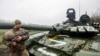 Український військовий біля пошкодженого російського танка Т-72БЗ під час масштабного вторгнення Росії до України. Донецька область, 13 квітня 2022 року