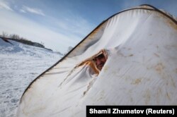 Рыбак, сидящий в палатке, установленной на замерзшем Иртыше. Аксу, 22 марта 2018 года.
