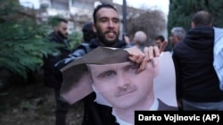 ბელგრადში, სირიის საელჩოს წინ კაცი ხევს სირიის პრეზიდენტის, ბაშარ ასადის ფოტოს. 8 დეკემბერი, 2024 წელი