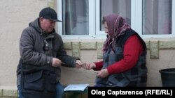 Un poștaș îi oferă pensia unei bătrâne din satul Iepureni, comuna Cania, raionul Cantemir.