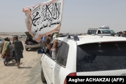 Ljudi mašu talibanskom zastavom u pograničnom pakistanskom grad Čaman 14. jula 2021, nakon tvrdnji talibana da su zauzeli grad Spin Boldak s druge strane granice u Avganistanu.
