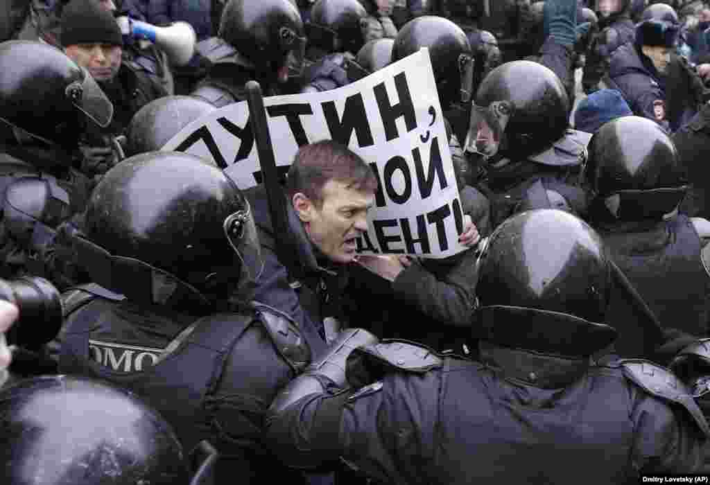 Російський ОМОН затримує протестуючого з плакатом із написом: &laquo;Путін, ти не мій президент&raquo; під час мітингу в Санкт-Петербурзі 28 січня. Мітинг &laquo;страйк виборців&raquo; був організований опозиційним діячем і борцем із корупцією Олексієм Навальним, який закликав своїх прихильників протестувати проти того, що його не допустили до участі у виборах президента Росії на підставі непогашеної судимості. Навальний був заарештований в Москві, оскільки викликані ним демонстрації проходили по всій країні. (AP/Dmitri Lovetsky)