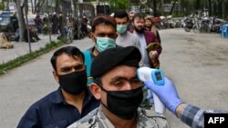 A health worker checks the body temperature of a devotee as a preventive measure against the COVID-19 coronavirus before Friday Prayers at a mosque in Kabul on April 24.