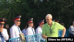 Гражданский проходит мимо полицейских, стоящих за металлическим ограждением.