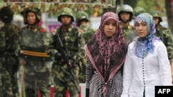 Ujguri su manjina većinom islamske vjeroispovijesti i žive u pokrajini Xinjiang, na sjeverozapadu Kine. (Foto: Ujgurske žene prolaze pored kineskih policajaca u ujgurskom okrugu grada Urumqi u kineskoj regiji Xinjiang, 14. jula 2009.)