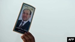 A man holds up a portrait of Prime Minister Nuri al-Maliki during a speech in Karbala ahead of the voting.