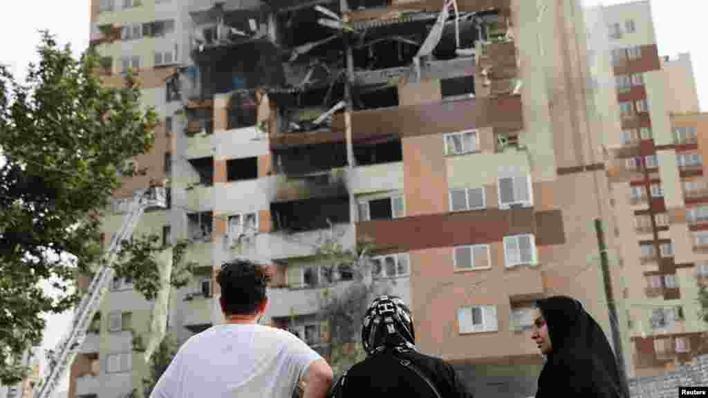People look at a damaged building in the aftermath of Israeli strikes in Tehran on June 13.