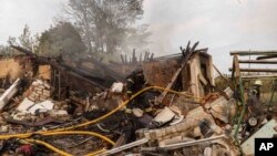 Український рятувальник гасить пожежу будинку після удару РФ по житловому кварталу в Черкаській Лозовій, Харківська область, Україна, 31 серпня 2024 року