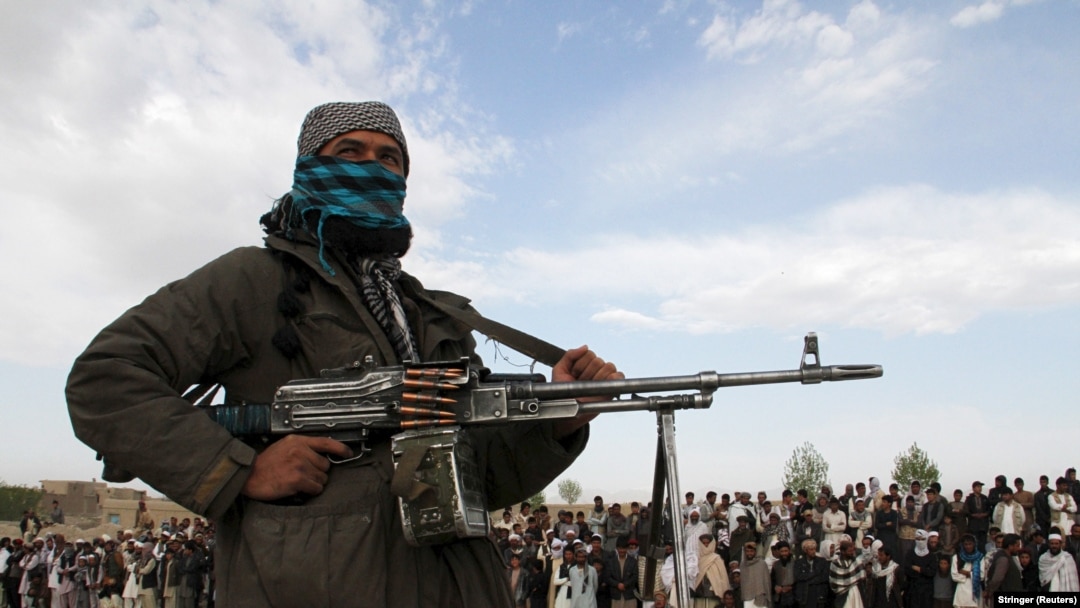 افغانستان - یکی از اعضای طالبان و دیگر افراد در محل اعدام ۳ مرد در ولایت غزنی در ۱۸ اپریل ۲۰۱۵ ایستاده‌اند.