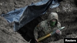 Український військовослужбовець тримає артилерійський снаряд, готуючись вистрілити з гаубиці в бік російських військ, 4 березня 2024 року