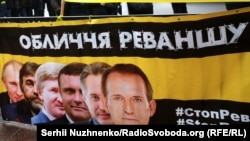 Плакат із зображенням українських олігархів і президента Росії Володимира Путіна під час акції «Стоп Реванш» біля Верховної Ради України. Перший у шерензі – Віктор Медведчук. За ним Дмитро Фірташ, Сергій Льовочкін, Рінат Ахметов і Вадим Новинський. Київ, 16 січня 2018 року 