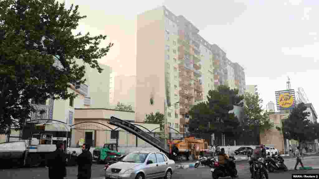 People gather around a damaged building in the aftermath of Israeli strikes in Tehran.
