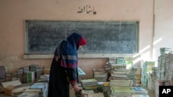 Učiteljica skuplja knjige u školi u Kabulu, Afganistan, u decembru 2022.