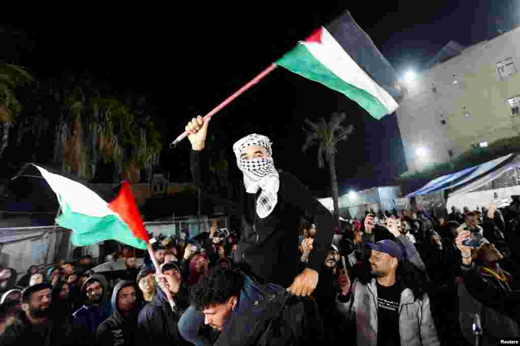 Muškarac maše palestinskim zastavama dok Palestinci reagiraju na vijesti o sporazumu o prekidu vatre s Izraelom, u Deir al-Balahu. 