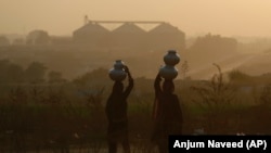 Pakistani nomad women carry water to their houses in a hazy evening on the outskirts of Islamabad. (file photo)
