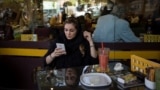O femeie din Iran își folosește telefonul într-o cafenea din Teheran (fotografie de arhivă). 