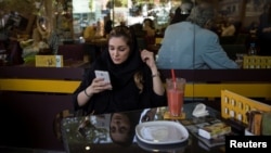 Iranka sa mobitelom u kafiću u Teheranu (arhivska fotografija)