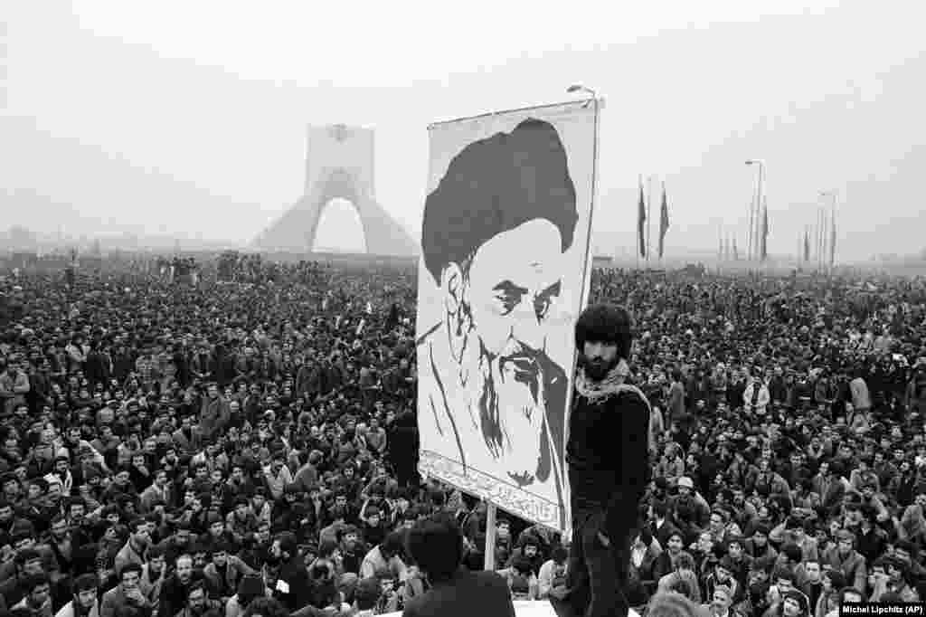 Demonstranti drže transparent s likom progranog islamskog vođe ajatolaha Homeinija dok se masa ljudi na ulicama u Teheranu povećava. Ove demonstracije od 10. decembra 1978. desile su se pored spomenika Šajah koji je izgrađen kako bi ovjekovječio vladavinu i moć monarha. 