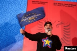 Liderul Partidului Socialist și prim-ministru al Albaniei, Edi Rama, flutură un steag în timp ce își ține discursul de la mitingul electoral de la Fier, Albania, pe 7 mai 2025.